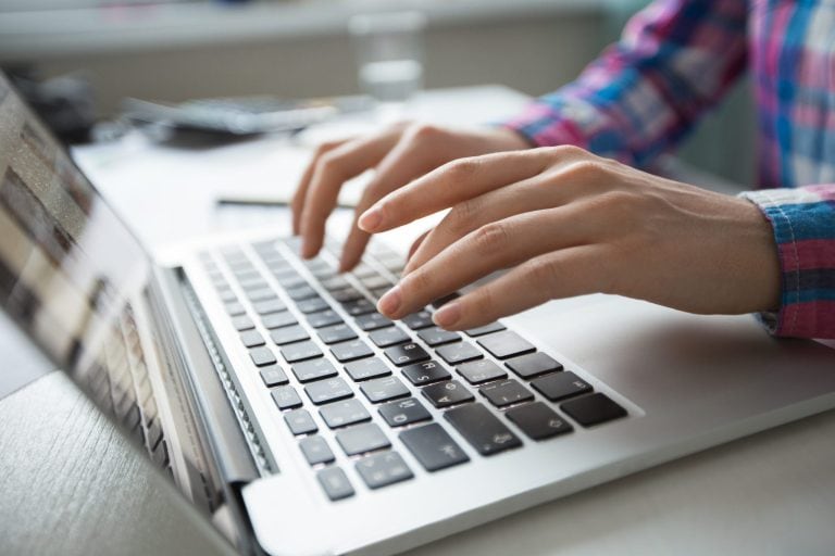 A close-up of a a woman's hands typing on her laptop